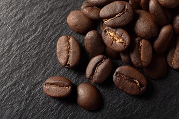 Naklejka premium Dark roasted coffee beans scattered on a slate surface ready for brewing