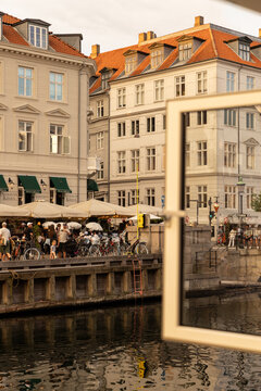 Windows at waterfront restaurant looking out at Nyhavn canal during summer with golden light 