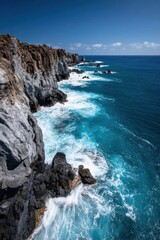 Waves crashing against rocky cliffs under a clear blue sky on a bright sunny day