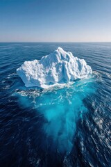 Iceberg floating in clear blue ocean water under bright sunlight during midday in a serene coastal area