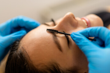 Young female client receiving a professional brow lamination (also known as a non-surgical brow lift) in a clean, modern beauty salon.