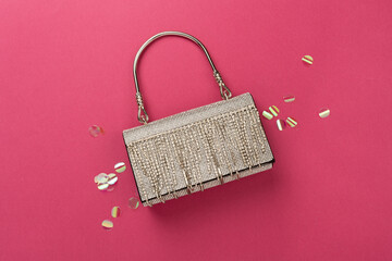 Handbag with beads on color background, top view