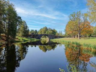 A bridge spans a river with a reflection of the trees in the water.