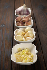 Variety of Garlic Forms Displayed in Bowls on Rustic Wooden Table
