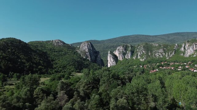 Aerial view of Jerma Canyon in Serbia with a small village surrounded by rocky cliffs and green forest. Horizontal 4k footage