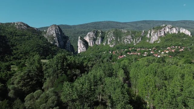 Aerial view of Jerma Canyon in Serbia with a small village surrounded by rocky cliffs and green forest. Horizontal 4k footage