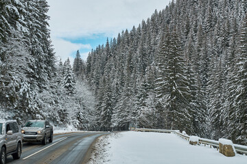 SUVs driving on a snowy mountain road in winter.