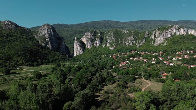 Aerial view of Jerma Canyon in Serbia with a small village surrounded by rocky cliffs and green forest. Horizontal 4k footage