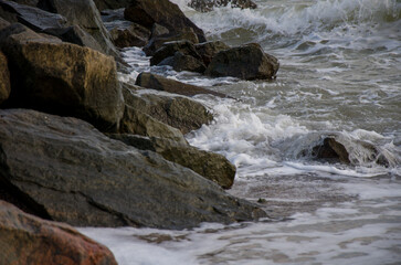 Rough ocean waves crashing against dark coastal rocks.
