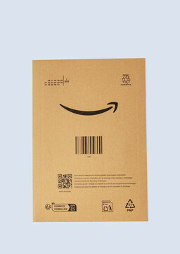 Padova, Italy - September 18, 2025: Amazon packaging box with barcode and logo displayed on a plain blue background, showcasing e-commerce delivery and branding elements