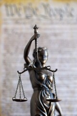 Lady Justice statue with scales on background of US Constitution page close up. Lawsuit and...
