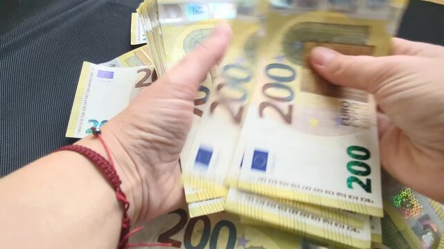 200 Euro banknotes demonstration: counting money in hand against black background