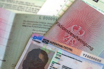 German Permanent resident card and temporary document lies on tax form close up. Aufenthaltstitel and Fiktionsbescheinigung