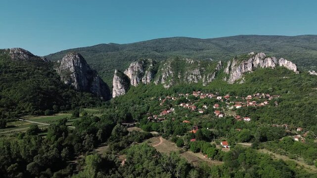 Aerial view of Jerma Canyon in Serbia with a small village surrounded by rocky cliffs and green forest. Horizontal 4k footage