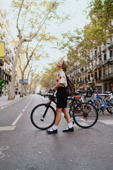 Obraz premium Young smiling Asian woman stands confidently with bike on dedicated lane, facing camera directly, representing mobility, eco-awareness, and morning readiness in modern city life.