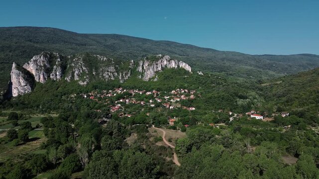 Aerial view of Jerma Canyon in Serbia with a small village surrounded by rocky cliffs and green forest. Horizontal 4k footage