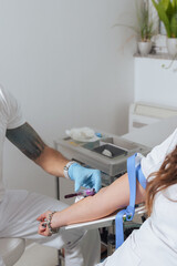 Lab professional taking a blood sample from a vein in a young pretty woman's arm. Blood draw concept.