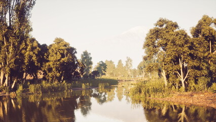 A tranquil river reflects the early morning light, flanked by vibrant greenery and tall trees. The peaceful atmosphere invites relaxation and appreciation of natures beauty.