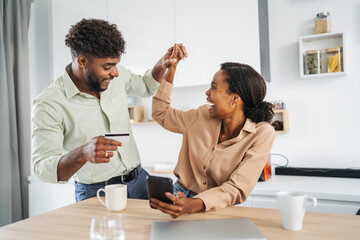 Happy couple celebrating successful online shopping purchase