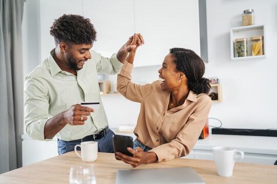 Happy couple celebrating successful online shopping purchase