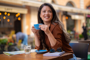 Smiling woman enjoying coffee at outdoor street cafe