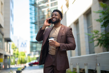 Happy businessman talking on phone holding coffee