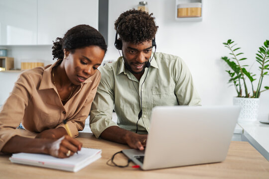 Black couple working remotely together in kitchen