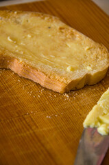 Thickly Buttered Slice of Bread on a Wooden Cutting Board with a Knife