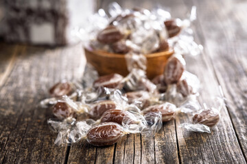 Sweet bonbon candies wrapped in foil on wooden table.