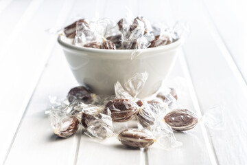 Sweet bonbon candies wrapped in foil on white table.