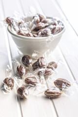 Sweet bonbon candies wrapped in foil on white table.