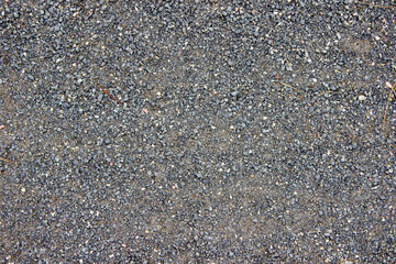Textured gravel surface with a mix of small stones and dirt, creating a natural earthy background ideal for various design projects and artistic applications