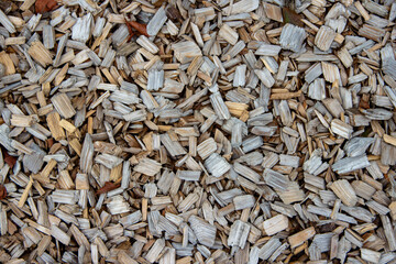Natural wood mulch covering ground surface, featuring a mix of light and dark tones, creating an organic texture ideal for landscaping and gardening projects