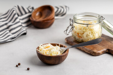 Homemade sauerkraut with carrots in a wooden bowl and glass jar.