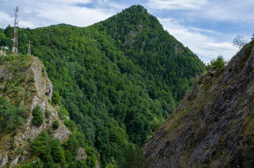 Lush Green Mountain Peak and Rocky Gorge with a Communications Mast under a Blue Sky