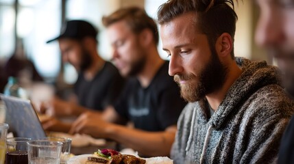 A group of men working on laptops and eating lunch together in a casual cafe setting fostering collabo n and productivity