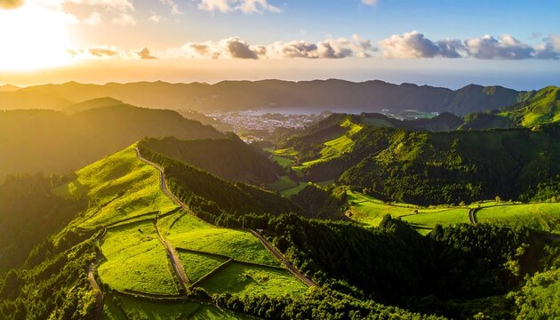 Aerial view of vibrant green rolling hills and valleys bathed in golden sunset light. A town sits nestled in the distance near the ocean