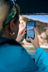 Tourist capturing ballestas islands landscape with smartphone