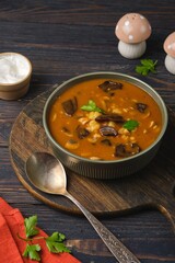Hungarian mushroom soup with potatoes, wild mushrooms, champignons, and paprika in a green bowl on a dark wooden platter. Soup recipes.
