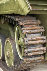 Rusty tank wheel and tracks. Detailed shot of a rusted tank wheel with chained tracks, green paint...
