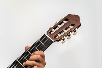Young hand playing classical acoustic guitar fretboard