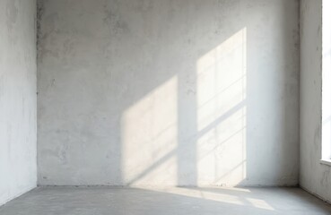 Obraz premium Empty room interior with rough concrete walls and floor. Sunlight streams through window creating geometric shadows on plaster surface. Bare space ready for renovation or staging. Modern loft style.