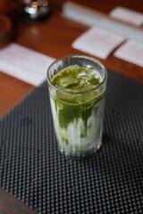 Enjoy refreshing iced matcha latte in a clear glass, perfect for a healthy lifestyle or trendy cafe menu, showcasing vibrant green tea and creamy milk swirls