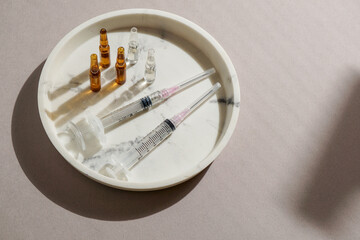 flat lay of various syringes, ampoules, medical gloves, disposable cap arranged on a light...