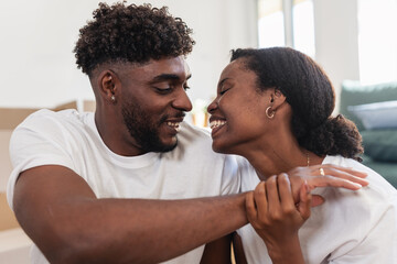 Affectionate African American couple sitting close together indoors, touching foreheads and smiling lovingly, expressing warmth, tenderness, emotional connection, and a happy romantic relationship
