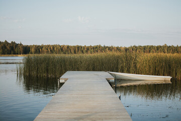 Naklejka premium Wooden pier and boat on a calm lake in summer in Estonia