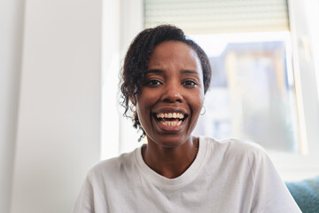 Young Black woman mid-conversation during a video call, expressive and emotionally engaged while speaking to a friend or family member from her home