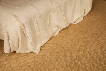 Obraz premium Soft beige bedspread drapes over a textured golden rug in a calm bedroom setting