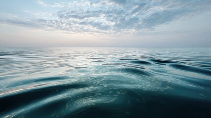 Obraz premium Calm Ocean Waves Under a Soft Blue Sky with Gentle Clouds Reflecting on the Water Surface, Evoking Serenity and Tranquility in Nature's Beautiful Scene