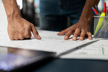 Close up of male urban developer reviewing layout plans for a new building construction, studying...